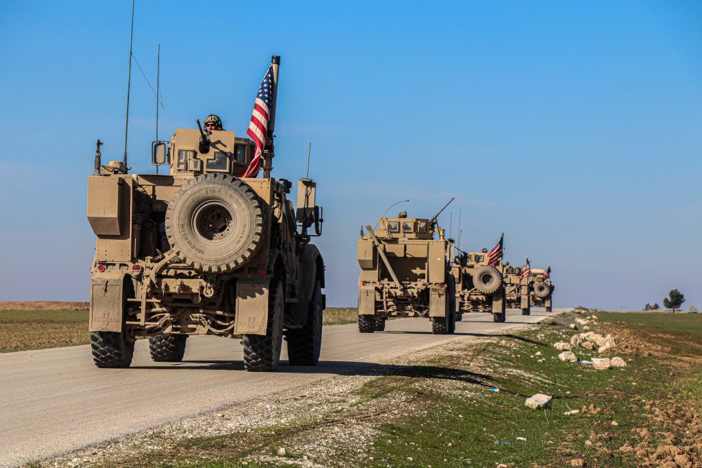 Photo of military tanks driving down a road to represent our background with the tactical defense industry